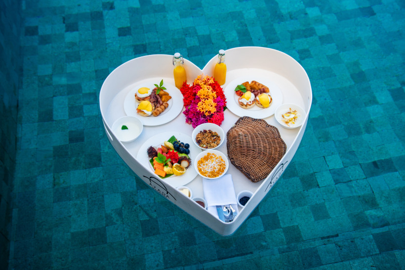 Malediven Ein romantisches Frühstück auf einem schwimmenden Tablett in Herzform, serviert im Pool. Frische Früchte, Eier, Säfte und Müsli sorgen für einen perfekten Start in den Tag in luxuriösem Ambiente.