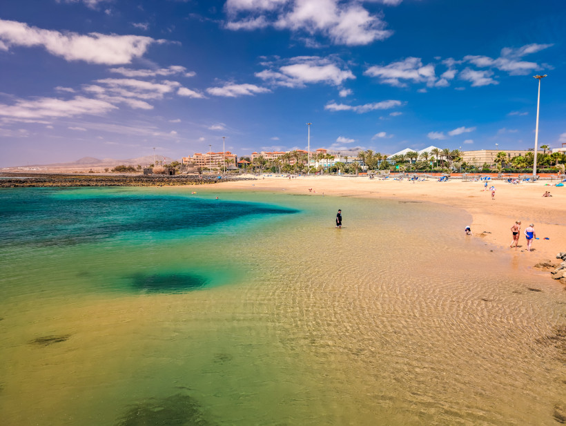 Sandstrand und flache Bucht mit türkisfarbenem Wasser in Caleta de Fuste