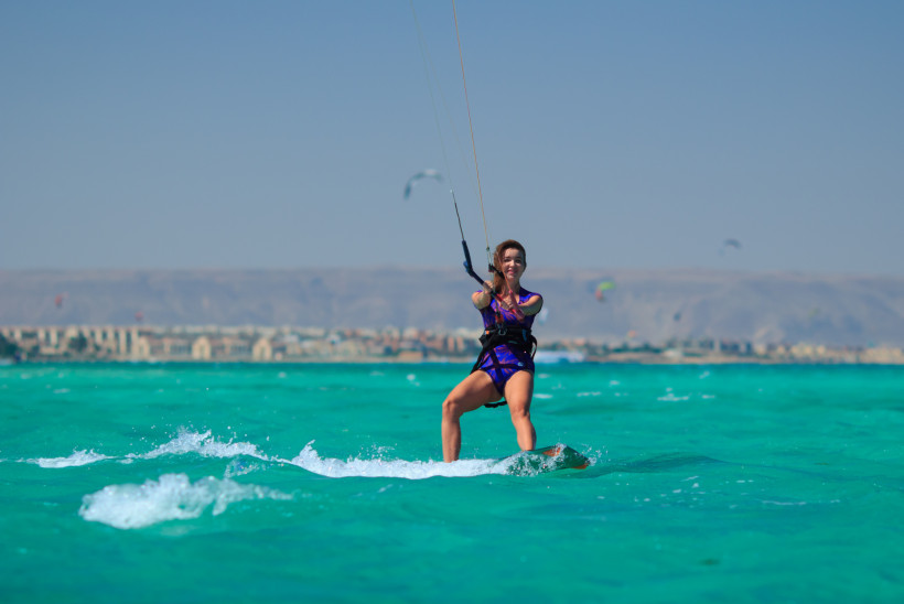 Frau beim Kitesurfen auf dem türkisfarbenen Meer von Hurghada bei idealen Windbedingungen