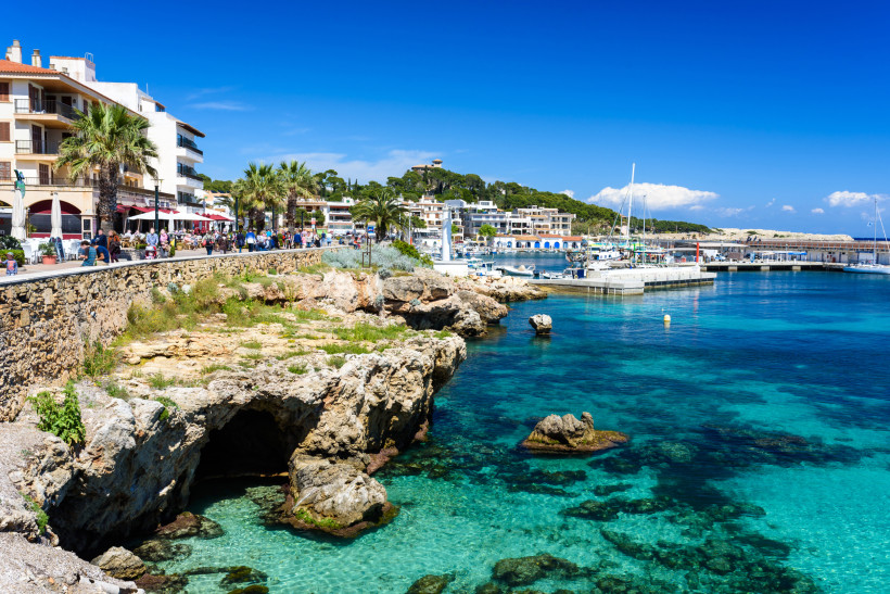 Promenade von Cala Ratjada mit Hafen, Booten, Restaurants und türkisfarbenem Wasser auf Mallorca