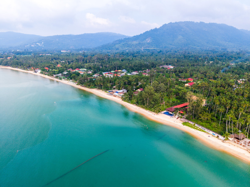 Luftaufnahme vom Lipa Noi Beach auf Koh Samui mit türkisblauem Meer, Palmen und grünen Bergen – idyllischer Strand für Ruhesuchende und Naturliebhaber.