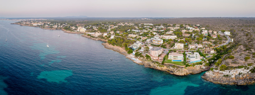 Luftaufnahme eines felsigen Küstenabschnitts mit Wohnhäusern am Meer, ähnlich Cala Blava