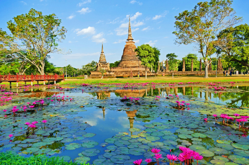 Stupas und Teich mit rosa Seerosen im Geschichtspark von Sukhothai, UNESCO-Weltkulturerbe in Thailand