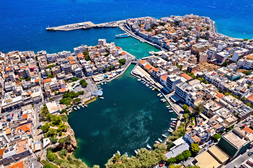 Luftaufnahme des Voulismeni-Sees in Agios Nikolaos mit Hafenbecken, Booten und umliegender Stadtbebauung