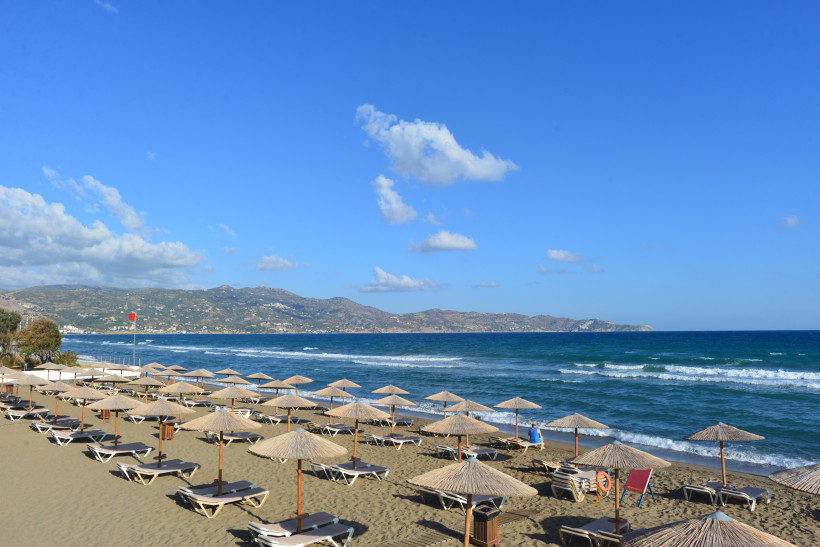 Amoudara Strand bei Heraklion mit Liegen und Sonnenschirmen am Sandstrand, Blick auf das Meer und die Küste