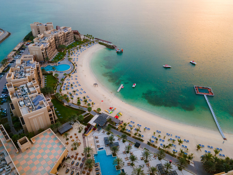 Luftaufnahme eines Luxusresorts mit Strand, Pool, Steg und türkisfarbenem Meer in Ras Al Khaimah – Vereinigte Arabische Emirate.
