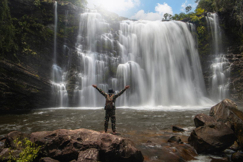 Khao Yai Nationalpark Thailand – beeindruckender Haew Suwat Wasserfall Mann steht vor dem majestätischen Haew Suwat Wasserfall im Khao Yai Nationalpark in Thailand, umgeben von Dschungel und Felsen.