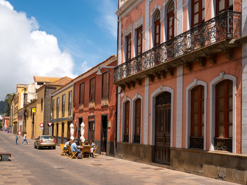 Historische Altstadt mit Straßencafé auf den Kanarischen Inseln Koloniale Straße mit bunt gestrichenen Häusern, Balkonfassaden und einem Straßencafé mit Menschen bei sonnigem Wetter