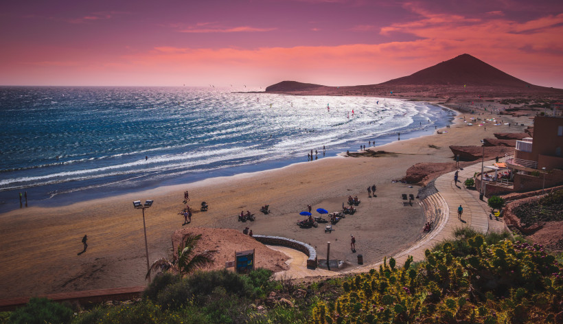Strand von El Médano bei Sonnenuntergang mit Montaña Roja und Kitesurfern auf Teneriffa