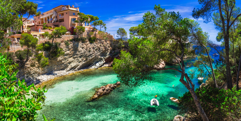Bucht Cala Fornells mit türkisfarbenem Wasser, Felsküste und Häusern am Hang