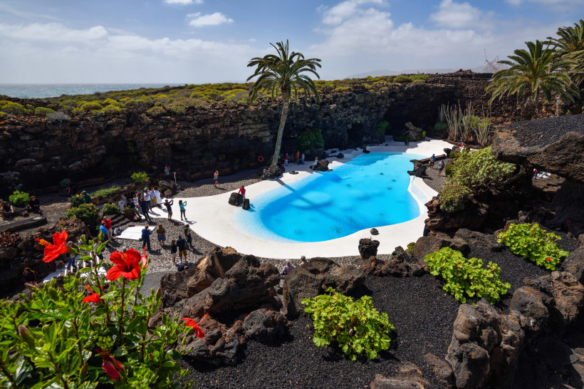 Jameos del Agua auf Lanzarote mit weißem Pool, Lavahöhle und Palmen – ikonisches Kunst- und Kulturprojekt von César Manrique