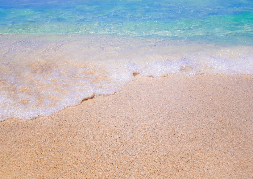 Sanfte Brandung und türkisfarbenes Meer am Sandstrand der Platja d’es Dolç