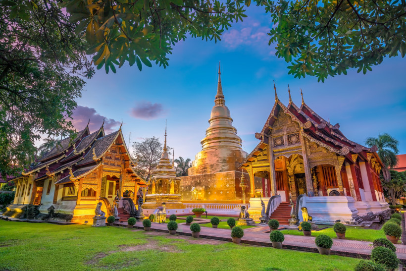 Goldene Tempelanlage Wat Phra Singh in Chiang Mai bei Sonnenuntergang, umgeben von historischen Gebäuden