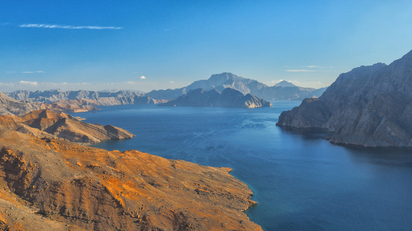 Blick über die Musandam-Fjorde im Oman mit felsigen Bergen und blauem Meer