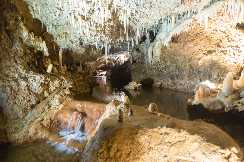 Harrison’s Cave auf Barbados mit Tropfsteinen, Wasserlauf und beleuchteten Felsen.