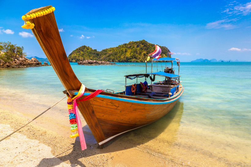 Thailand Longtail-Boot – Authentisches Inselhüpfen für kleines Budget Traditionelles Longtail-Boot am Strand von Thailand mit klarem Wasser und Inselkulisse – perfektes Motiv für budgetfreundliches Inselhüpfen und günstiges Reisen.