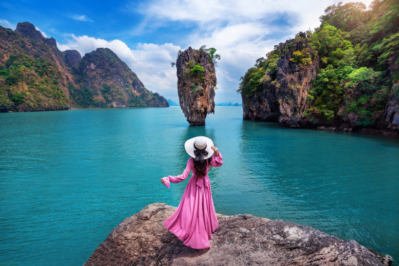 James Bond Island Aussichtspunkt – Phang-Nga-Bucht in Thailand Frau in pinkem Kleid am Aussichtspunkt mit Blick auf die ikonische Felseninsel James Bond Island in Thailands Phang-Nga-Bucht.
