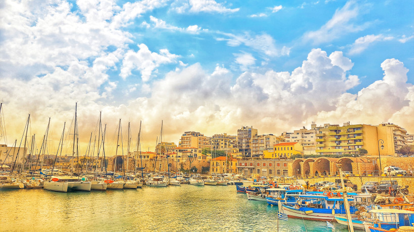 Heraklion: Blick auf den Hafen mit Booten und Uferbebauung Hafen von Heraklion mit Segelbooten und Stadtkulisse unter wolkigem Himmel