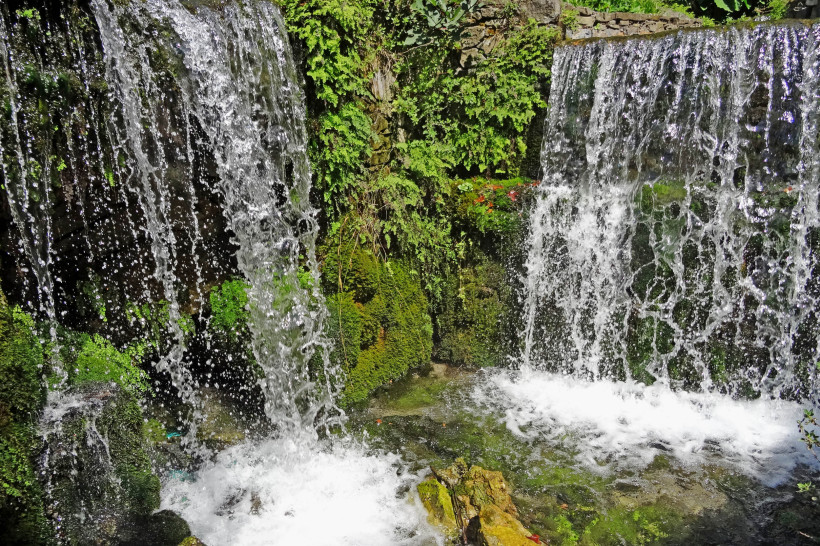 Argiroupoli Wasserfälle: Wasser stürzt über moosige Felsen in ein Becken Argiroupoli-Wasserfälle mit zwei herabstürzenden Wasserläufen über moosbewachsene Felsen