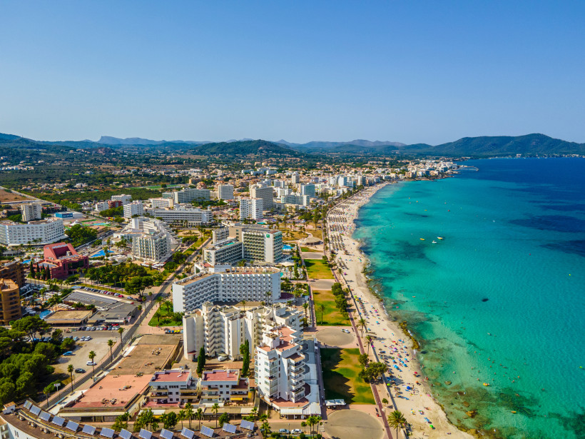 Luftaufnahme von Cala Millor mit Strandpromenade, Hotelgebäuden und türkisblauem Meer