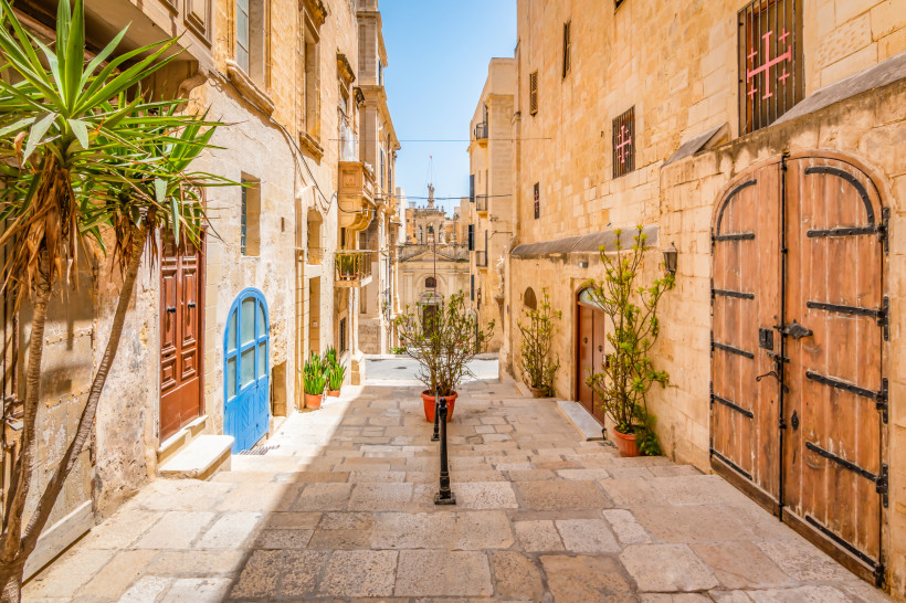 Maltas Altstadtgassen – mediterranes Flair in Valletta Enge Gasse in der Altstadt von Valletta auf Malta mit typischen Sandsteinfassaden, bunten Türen und Pflanzen im Sonnenschein