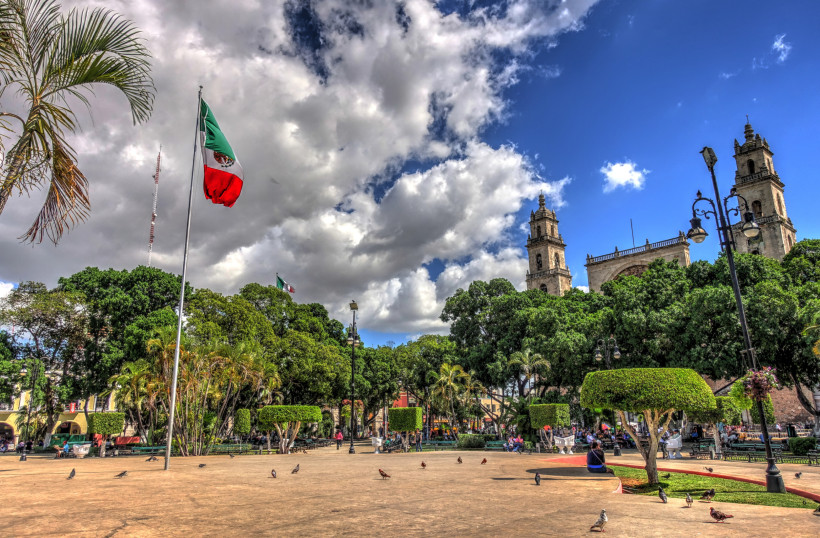 Stadt Mérida, Marktplatz, im Hintergrund Gebäude, Tauben, Menschen, mexikanische Fahne
