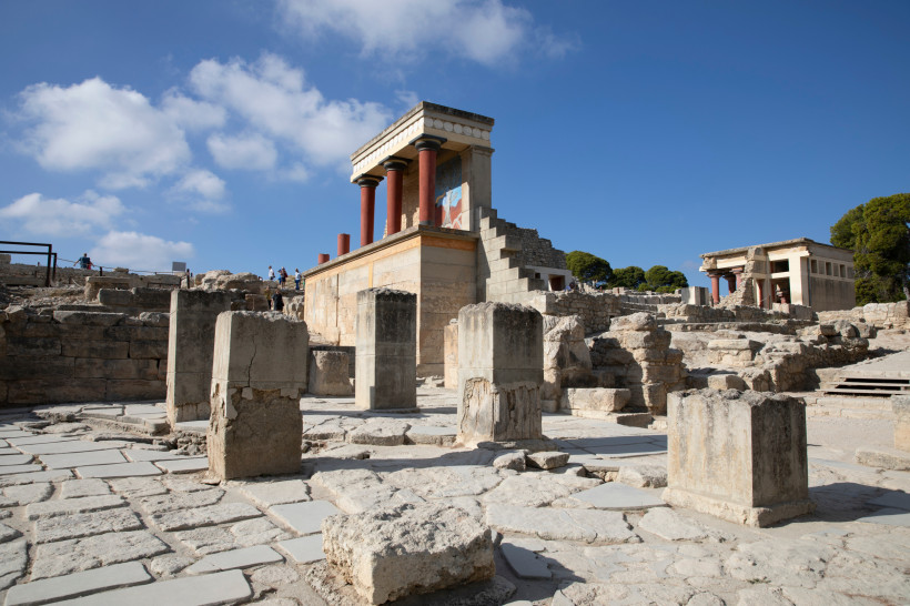 Ruinenbereich des Palasts von Knossos mit rekonstruierter Säulenfront und Steinmauern unter blauem Himmel