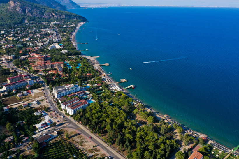Luftaufnahme von Beldibi an der Türkischen Riviera mit Strandhotels, langen Küstenabschnitten, türkisblauem Meer und dem Taurusgebirge im Hintergrund