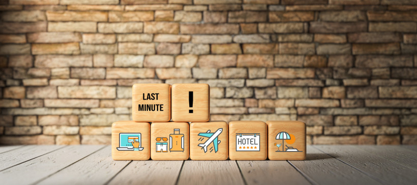 Last-Minute-Urlaub buchen – Flug, Hotel Holzwürfel mit Symbolen für Online-Buchung, Gepäck, Flugzeug, Hotel und Strand sowie Last-Minute-Hinweis – Visualisierung spontaner Urlaubsangebote