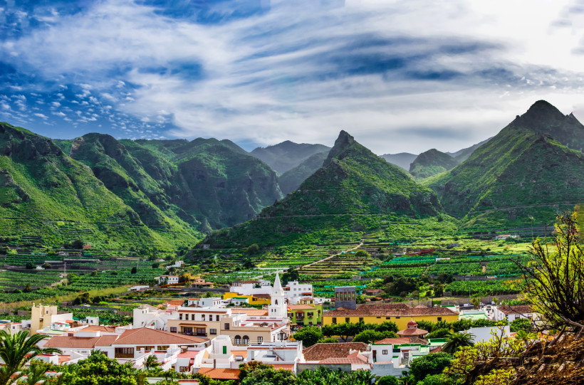 Saftige grüne Berge und ein traditionelles Dorf mit weißer Kirche auf Teneriffa