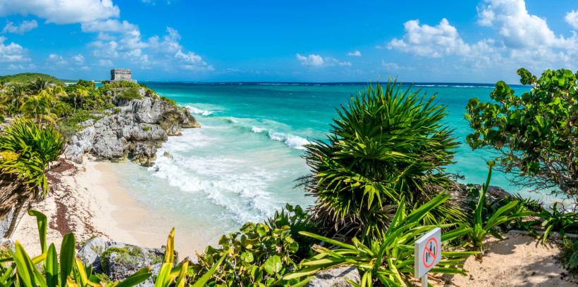 Strandferien, Mexiko Panoramaansicht der Ruinen von Tulum auf einer Klippe mit tropischer Vegetation, türkisblauem Meer und Wellen, die gegen den weißen Sandstrand schlagen