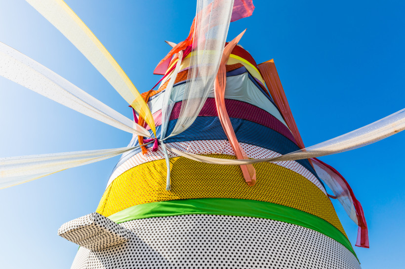 Ras al-Khaimah Art Festival Farbenfrohe Kunstinstallation mit bunten Stoffbahnen, die im Wind flattern, vor klarem blauem Himmel