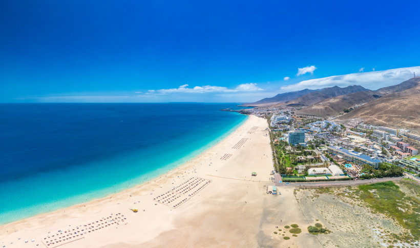 Luftaufnahme von Jandía Playa auf Fuerteventura mit langem Sandstrand, türkisblauem Meer und Hotelanlagen im Hintergrund