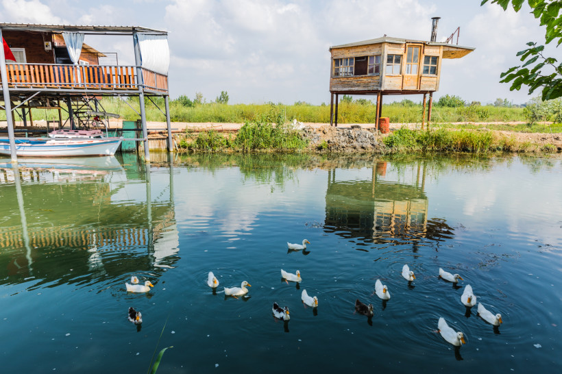 Bogazkent Flussgebiet – traditionelle Häuser am Köprüçay mit Enten und ruhiger Natur Holzhäuser am Fluss in Bogazkent mit schwimmenden Enten und grüner Uferlandschaft – typisch für die ruhige, naturbelassene Region.