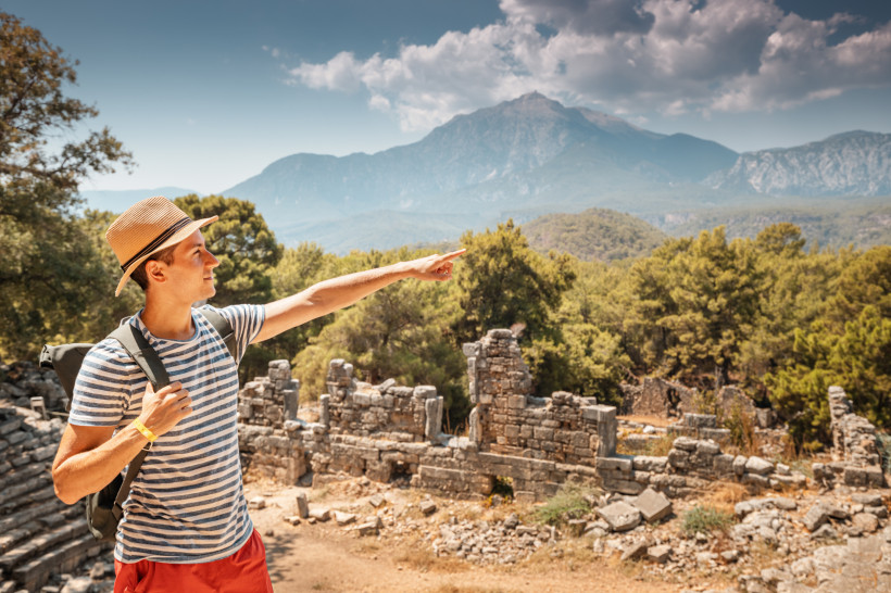 Besucher in der antiken Stadt Phaselis bei Kemer mit historischen Ruinen, Pinienwald und Blick auf das Taurusgebirge