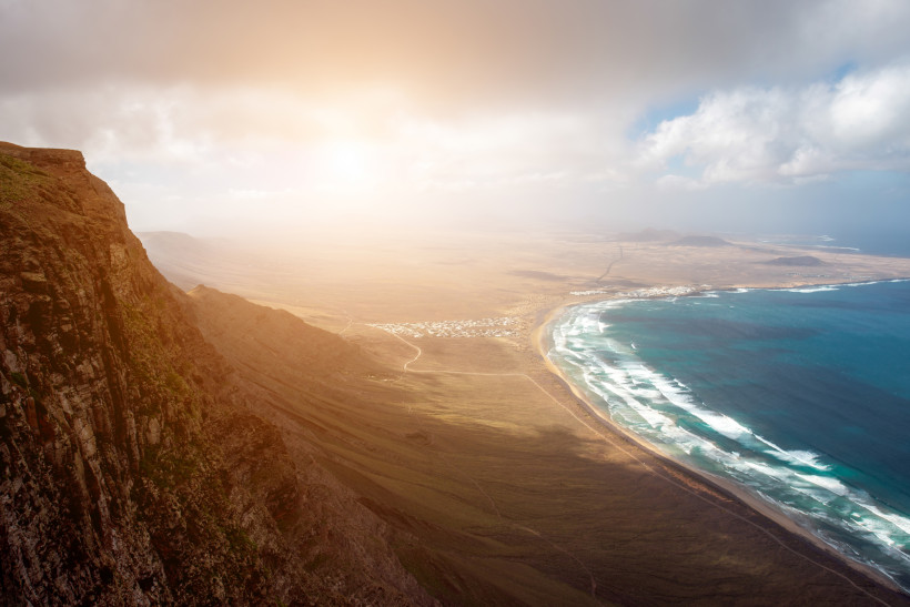 Famara: Spektakuläre Klippen und der wilde Surfstrand an Lanzarotes Nordküste Panorama der Famara-Klippen mit Blick auf den weitläufigen Surfstrand Playa de Famara auf Lanzarote
