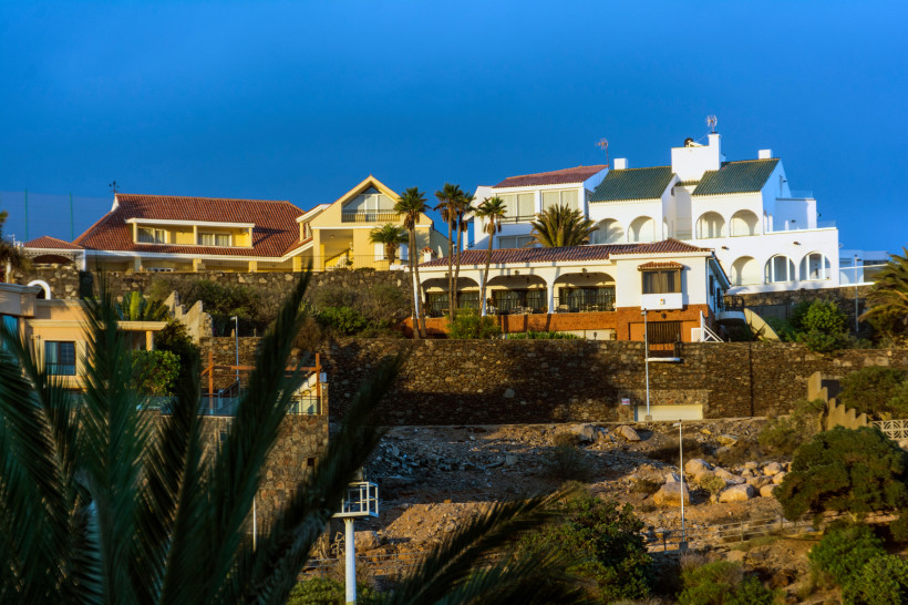 Häuser und Ferienanlagen an einer Küste in San Agustín auf Gran Canaria bei blauem Himmel