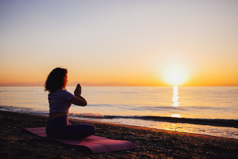 Person beim Yoga am Strand von Kemer während des Sonnenuntergangs