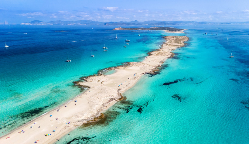 Luftaufnahme einer schmalen Sandbank mit Strand und Booten im türkisfarbenen Meer vor Formentera