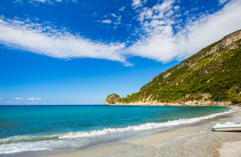 Ermones: Küstenlandschaft mit Kiesstrand und türkisfarbenem Meer Strand von Ermones mit türkisfarbenem Meer, Kiesufer und bewaldeter Küste unter blauem Himmel