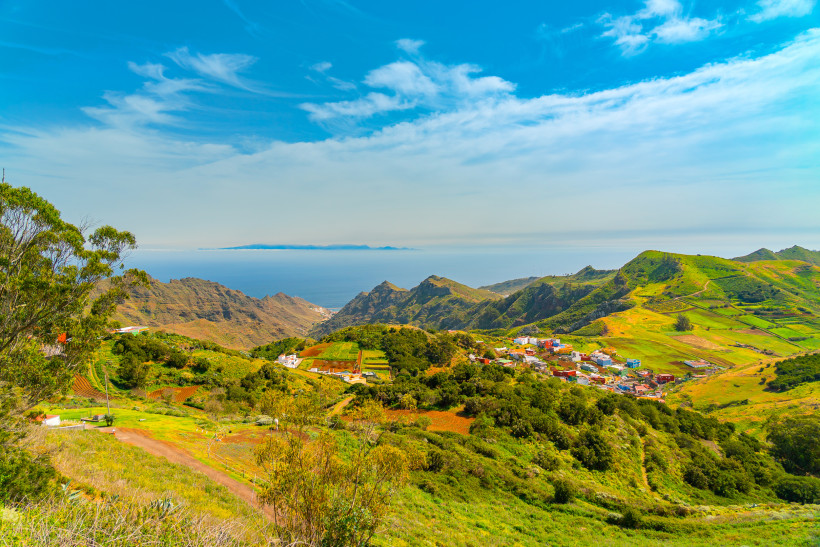 Atemberaubende Aussicht auf das grüne Inselinnere von Gran Canaria Blick auf die grüne Berglandschaft und das Meer im Inselinneren von Gran Canaria – malerische Dörfer, Felder und Hügel unter blauem Himmel mit Fernsicht auf den Atlantik.