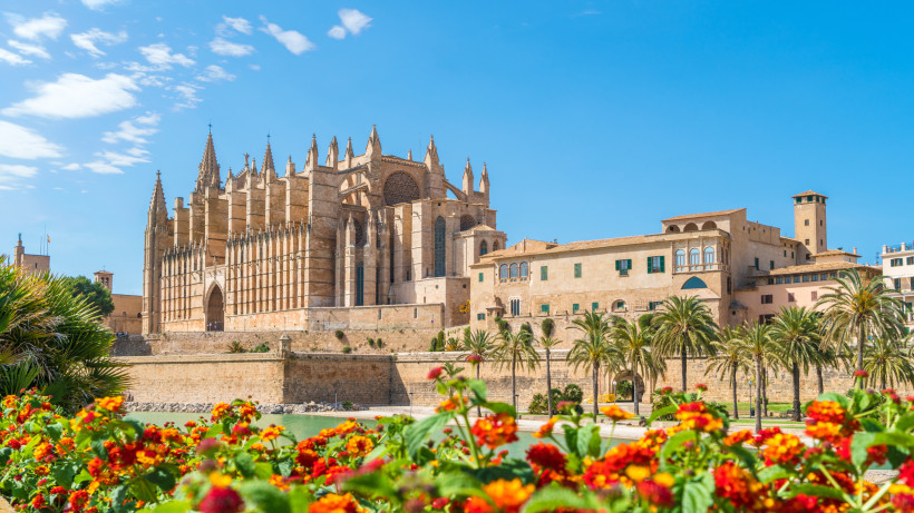 Kathedrale La Seu in Palma de Mallorca, Blick über die Stadtmauer mit Palmen und Blumen im Vordergrund