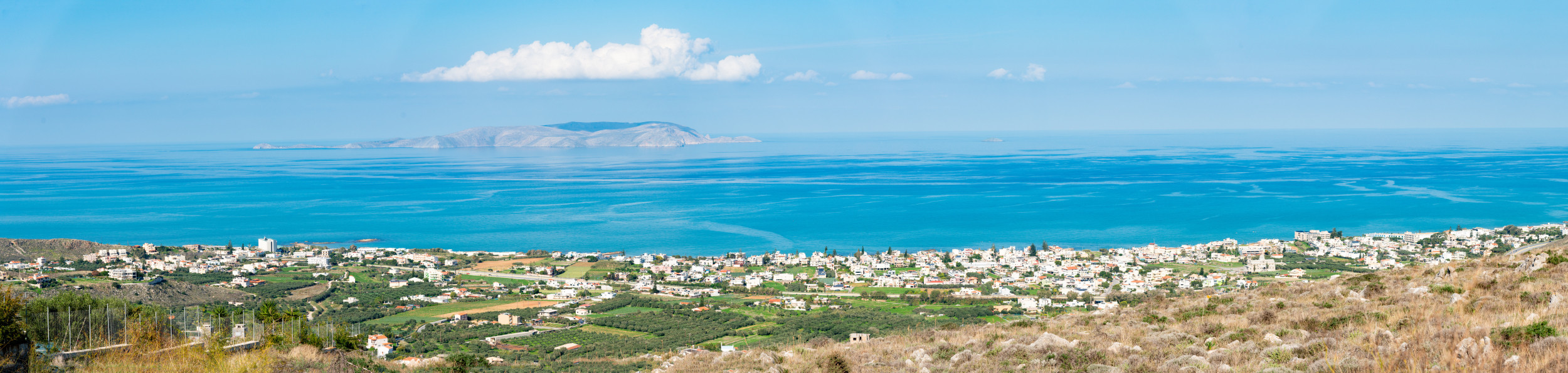 Küstenort Kokkini Hani auf Kreta mit Blick über Felder auf das Meer und eine vorgelagerte Insel