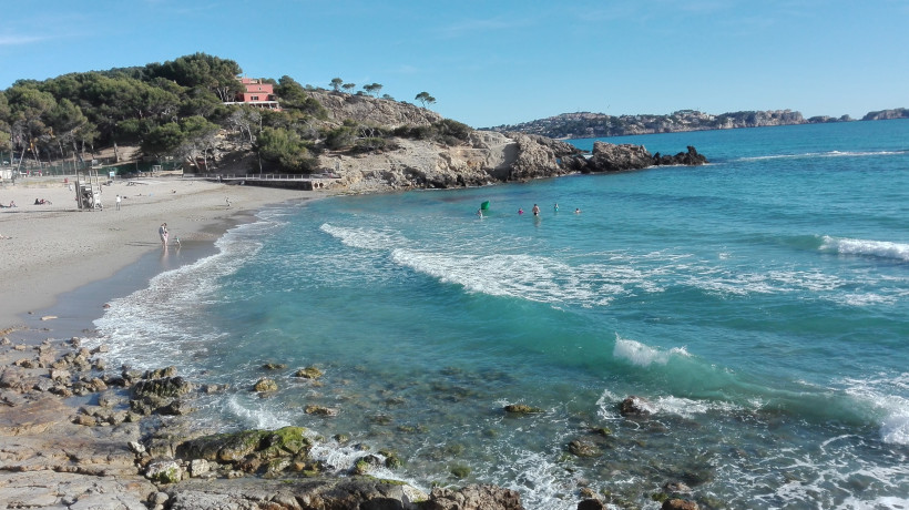 Bucht an der Playa La Romana mit Sandstrand, Felsen und türkisfarbenem Meer