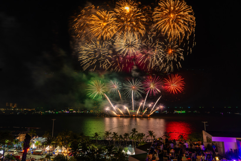 Thailand Pattaya Großes Feuerwerk über dem Meer in Pattaya bei Nacht. Am Strand und auf einer Rooftop-Bar feiern Menschen das farbenfrohe Spektakel.
