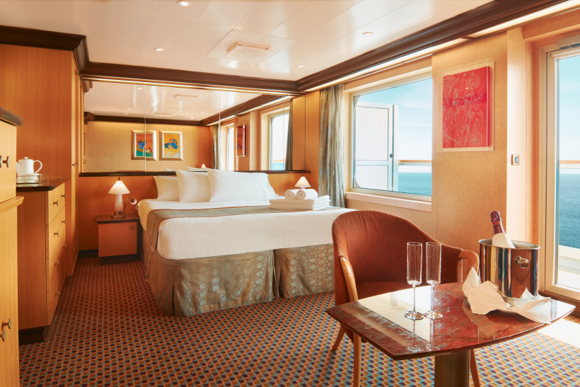 Costa Fascinosa – Grand Suite: Schlafzimmer mit Doppelbett, Sitzbereich und Balkon Schlafbereich der Grand Suite auf der Costa Fascinosa mit Doppelbett, Sitzgruppe und Balkonblick aufs Meer