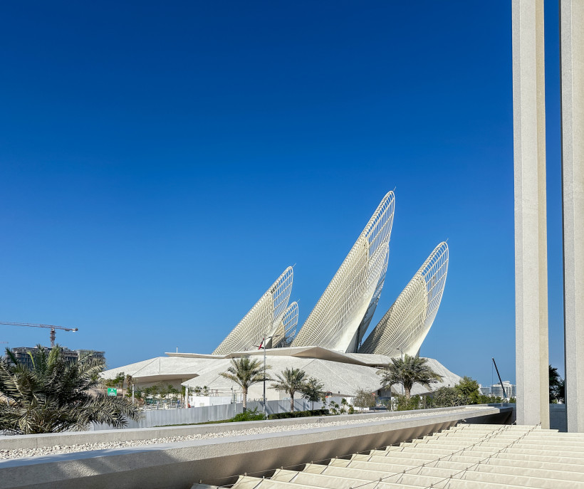 Außenansicht des modernen Abrahamic Family House in Abu Dhabi mit markanter Architektur und Palmen im Vordergrund