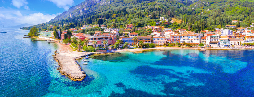 Ein atemberaubendes Panoramabild zeigt eine malerische Küstenstadt, die sich an einem türkisfarbenen Meer erstreckt.