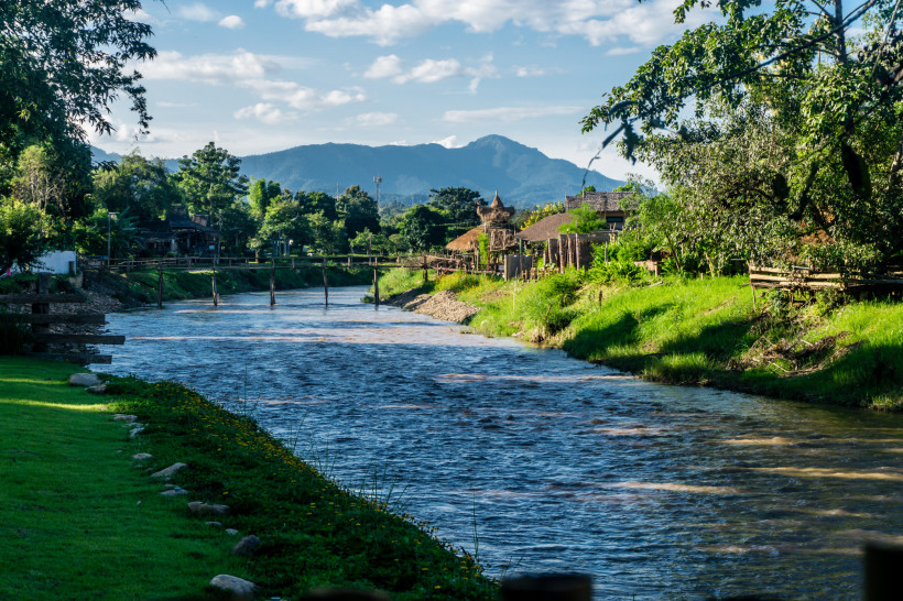 Ruhiger Fluss in Pai umgeben von grüner Natur und Bergen in Nordthailand