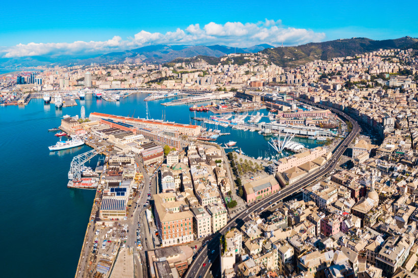 Luftaufnahme des Hafens von Genua mit Marina, Kreuzfahrtschiffen und Stadtbebauung am Küstenbogen